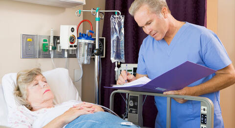concerned doctor with patient at hospital looking at journal.