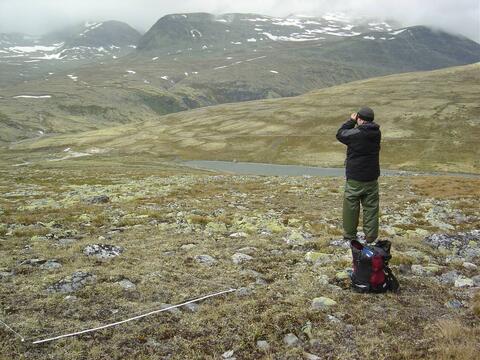 Landscape at Rondane with a sampling plot marked out and a person looking through binoculars