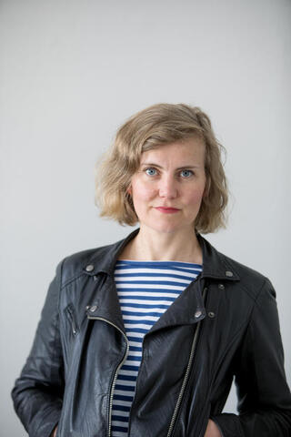 Portrait of woman with blonde hair, striped t shirt and leather jacket. 