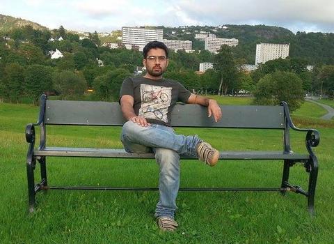 Syed sitting on a bench in a park