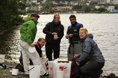 Five biology students performing sample work by the sea.