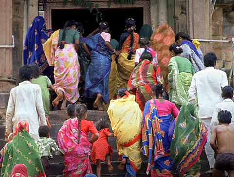 Indiske menn og kvinner i fargerike klær på vei opp en trapp til et tempel