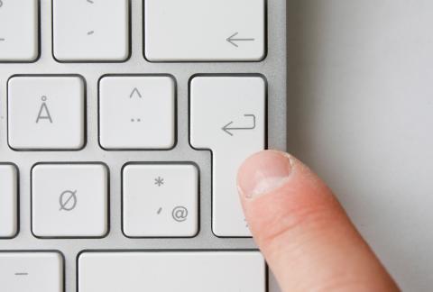 En finger som trykker på enterknappen på et tastatur