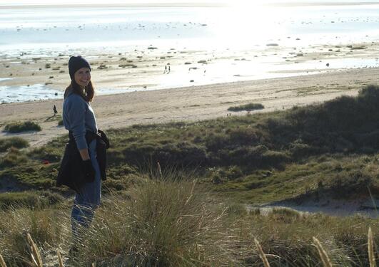 A young woman in winter clothing in front of a beach