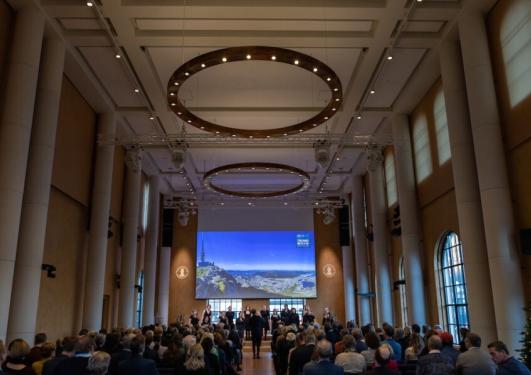 Bilde fra TMF årsmarkering i Universitetsaulaen. Mennesker på scenen og oversiktsbilde av mennesker i salen