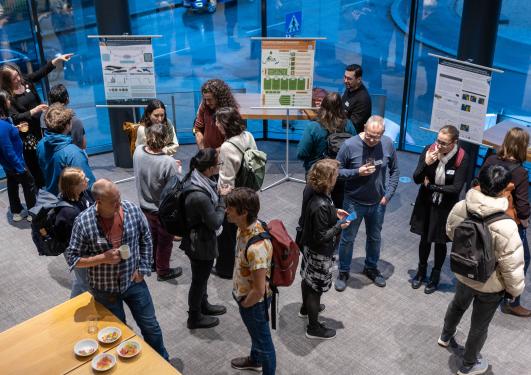 Image taken from above showing a group of conference participants engaged in conversation with 3 of the conference posters in the background