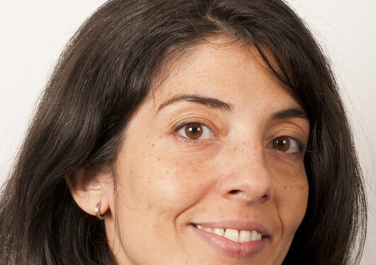 A woman with shoulder-length, dark brown hair and a dark top