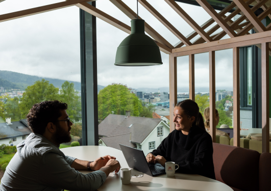 To studenter på sitter ved et bord på campus Bergen