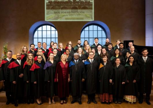 Alle de nye doktores står oppstilt på scenen sammen med fungerende rektor
