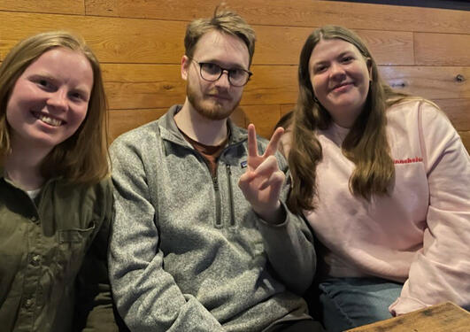 Amalie, Ole and Camilla sitting in a restaurant, posing for the camera.