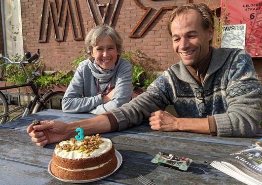 A woman, a man and a cake with a candle shaped as the number 3