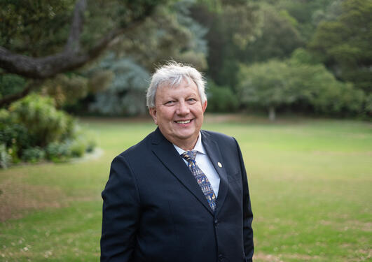 Portrait of a man in a black suit, green forest in the background