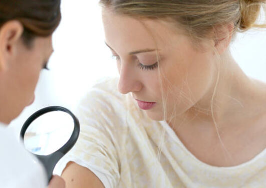 Doctor checking a patient's mole for cancer.