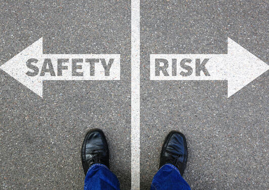 Bilde av to hvite piler på grått underlag.  Pilen til høyre med påskriften "Safety", den til høyre sier "Risk"