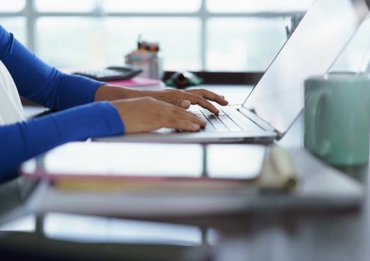 Bilde av studiesituasjon m. bærbar PC og hender