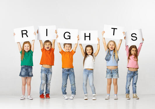 Glade barn som holder et skilt med teksten «rettigheter»