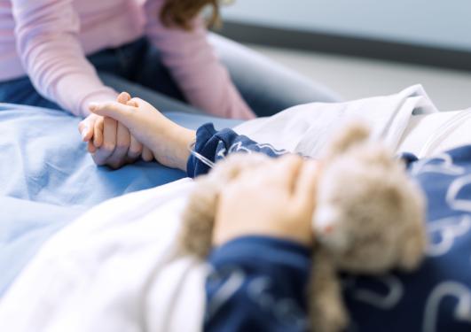 Mor og datter på sykehuset, mor holder barnet i hånden