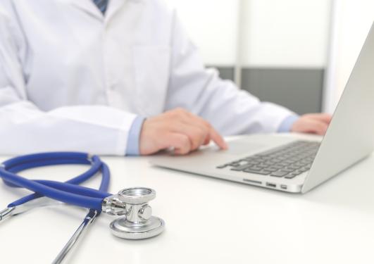 illustrasjonsbilde av en doktor som sitter med en bærbar PC