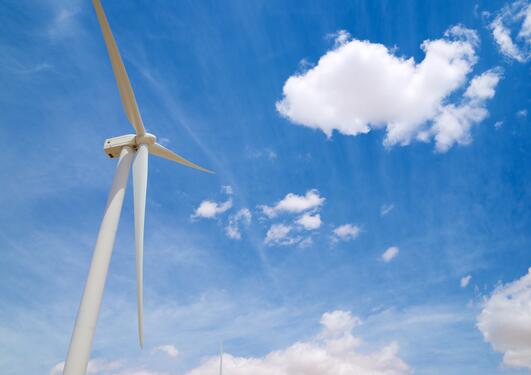 Image of a single windmill against a lightly clouded blue sky