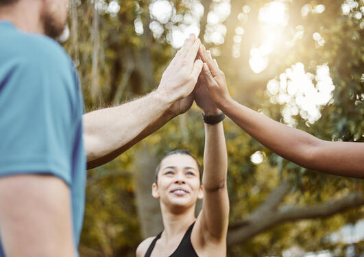 tre personer tar en high five i skogen
