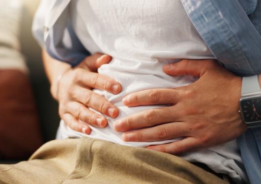 mann som holder seg på magen på grunn av magesmerter