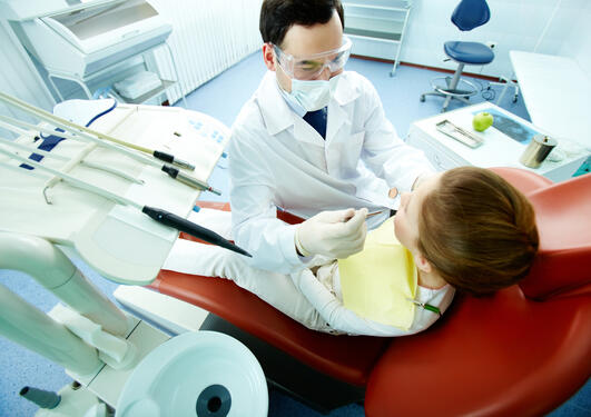 En tannlege behandler en gutt som sitter i tannlegestolen