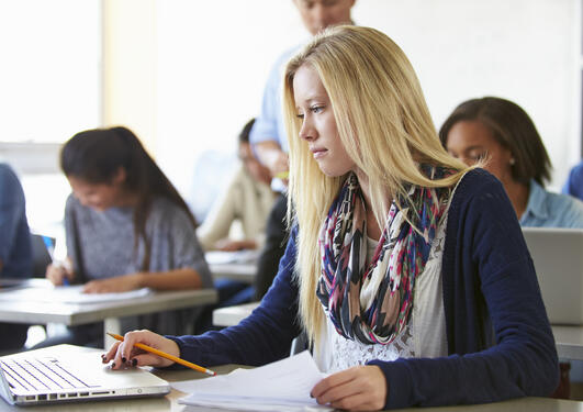 Ung kvinne som avlegger eksamen på laptop i klasserom