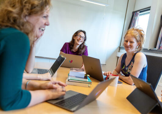 Forsker rundt et bord med hver sin laptop