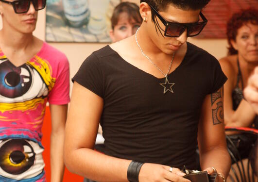 Gutt taster på sin mobil før konsert i Havana, Cuba. Den punkete sveisen er en kopi av frisyren til artistene som skal til å opptre.
