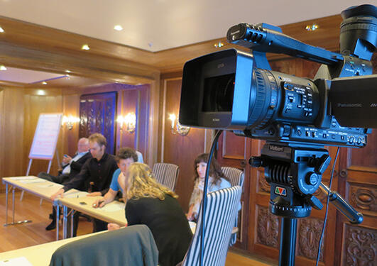 Nærbilete av tv-kamera, kursdelktakarar i bakgrunn