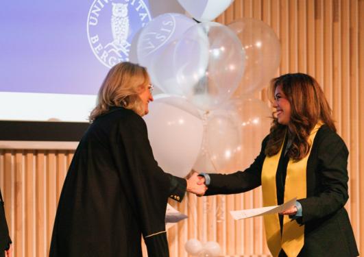 Maria Camila Salazar Patiño gratuleres av dekan Sigrid Schütz og LLM-fagansvrlig Ingrid Barlund