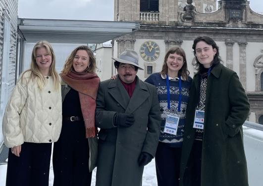 Five people posing in front of a an old building