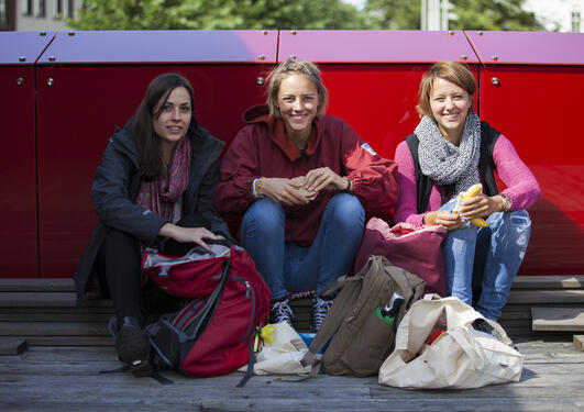 Three female students sitting in the sun, smiling