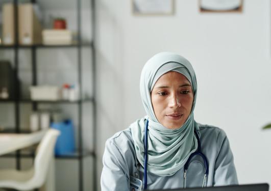 En ung muslimsk kvinne på jobb foran en pc