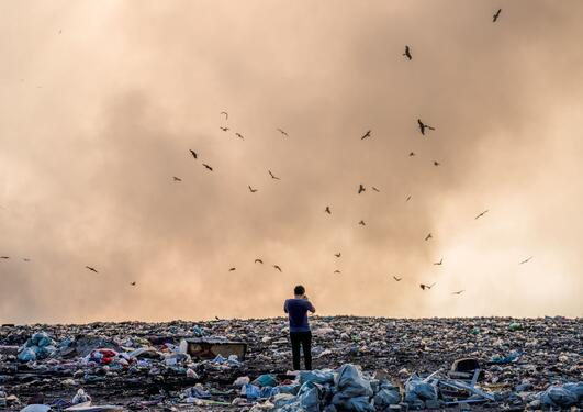 Man stands in pile of plastic litter and takes a photo