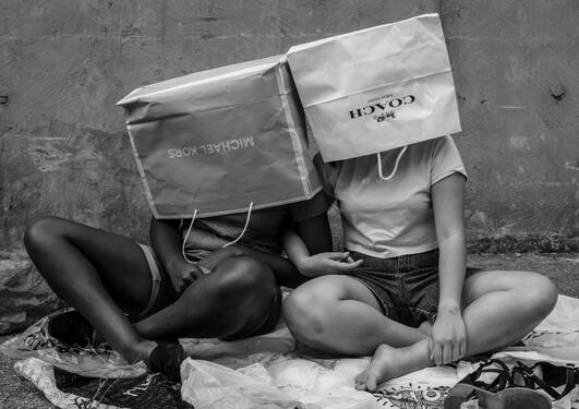 Two persons with their heads in paper shopping bags