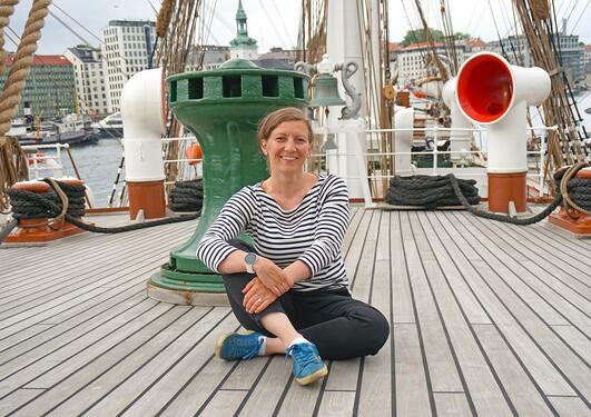 Katja Enberg sitting on the deck of the sailing vessel Statsraad Lehmkuhl.
