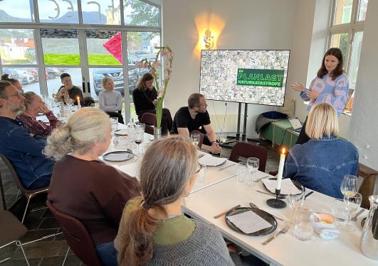 A group of people seated around a table with one person giving a presentation