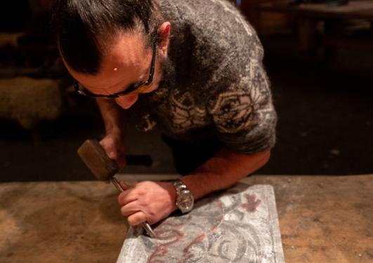 Bildet viser en mann som driver med treskjæring.