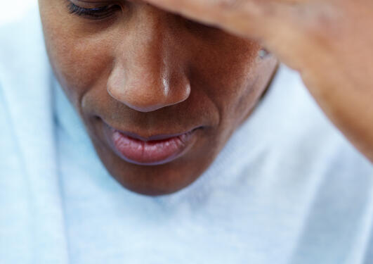 Black man looking down with head in hand