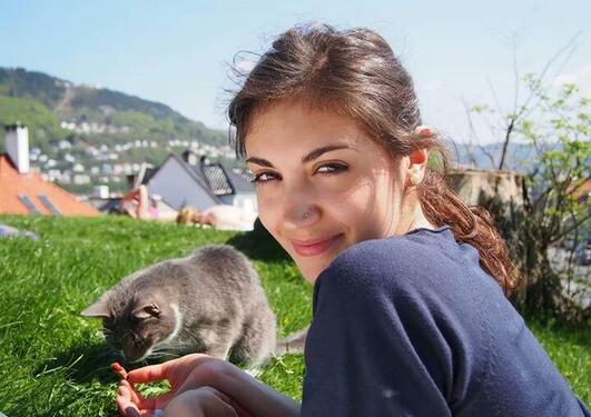 Photo of Martina and a grey cat enjoying the sun on a lawn at Klosteret in central Bergen