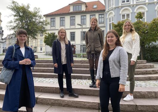 5 young women standing outside old buildings