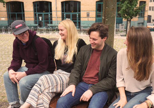 4 students sitting outside of the social sciences building