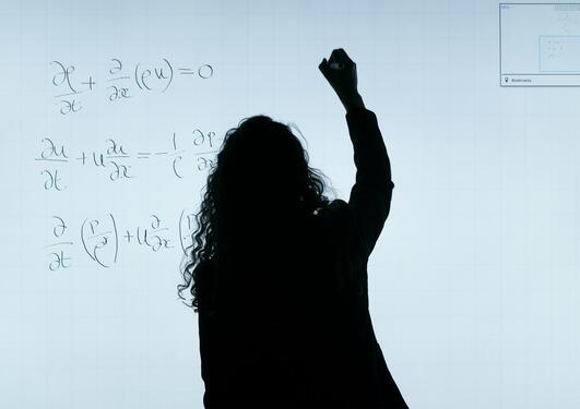 Woman writing mathematical formulas on a white board