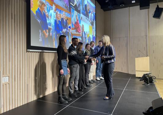 Sigrunn Eliassen deler ut prisen til en rekke studenter i Storsalen.