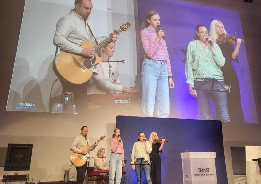 5 personer som spiller instrument og synger på en scene