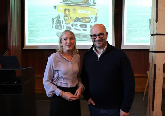 UiB-rektor Margareth Hagen og TV-produsent James Honeyborne foran bilde av UiBs undervansrobot Ægir
