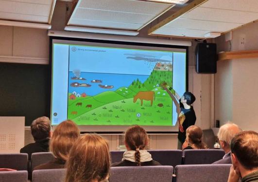 A group of people seated around a table with one person giving a presentation