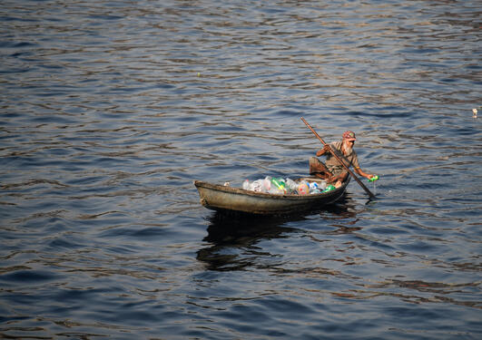 A man on a boat collects plastic bottles from polluted river Buriganga in Dhaka, Bangladesh.