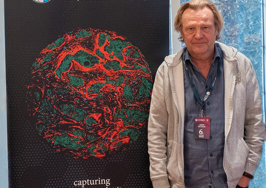 Arne Östman standing in front of a CCBIO poster.